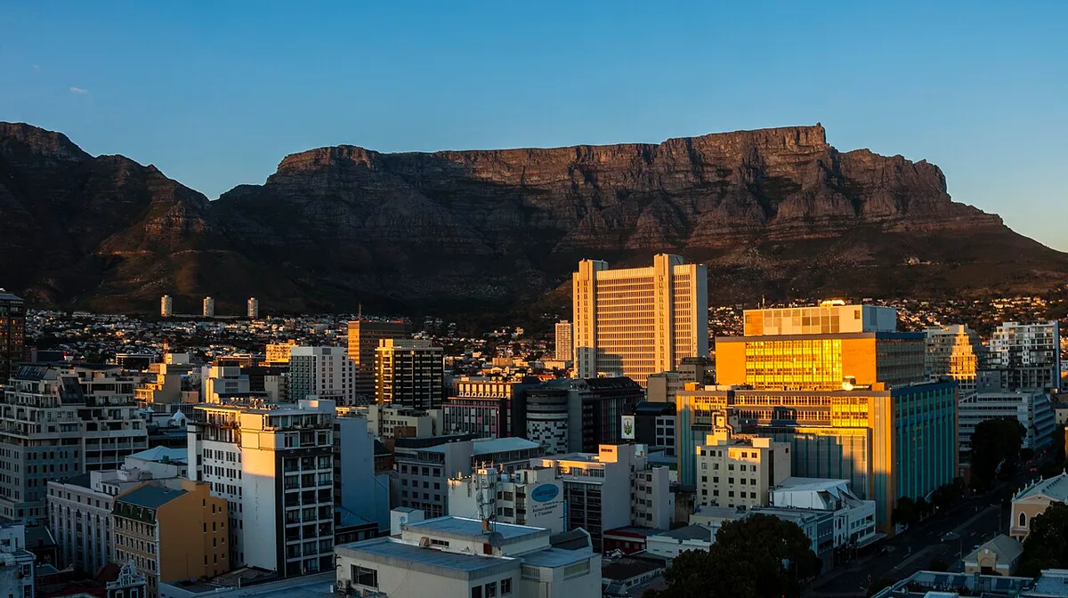 Une ville et une montagne se détachent en silhouette sous un ciel qui pâlit à l'aube.
